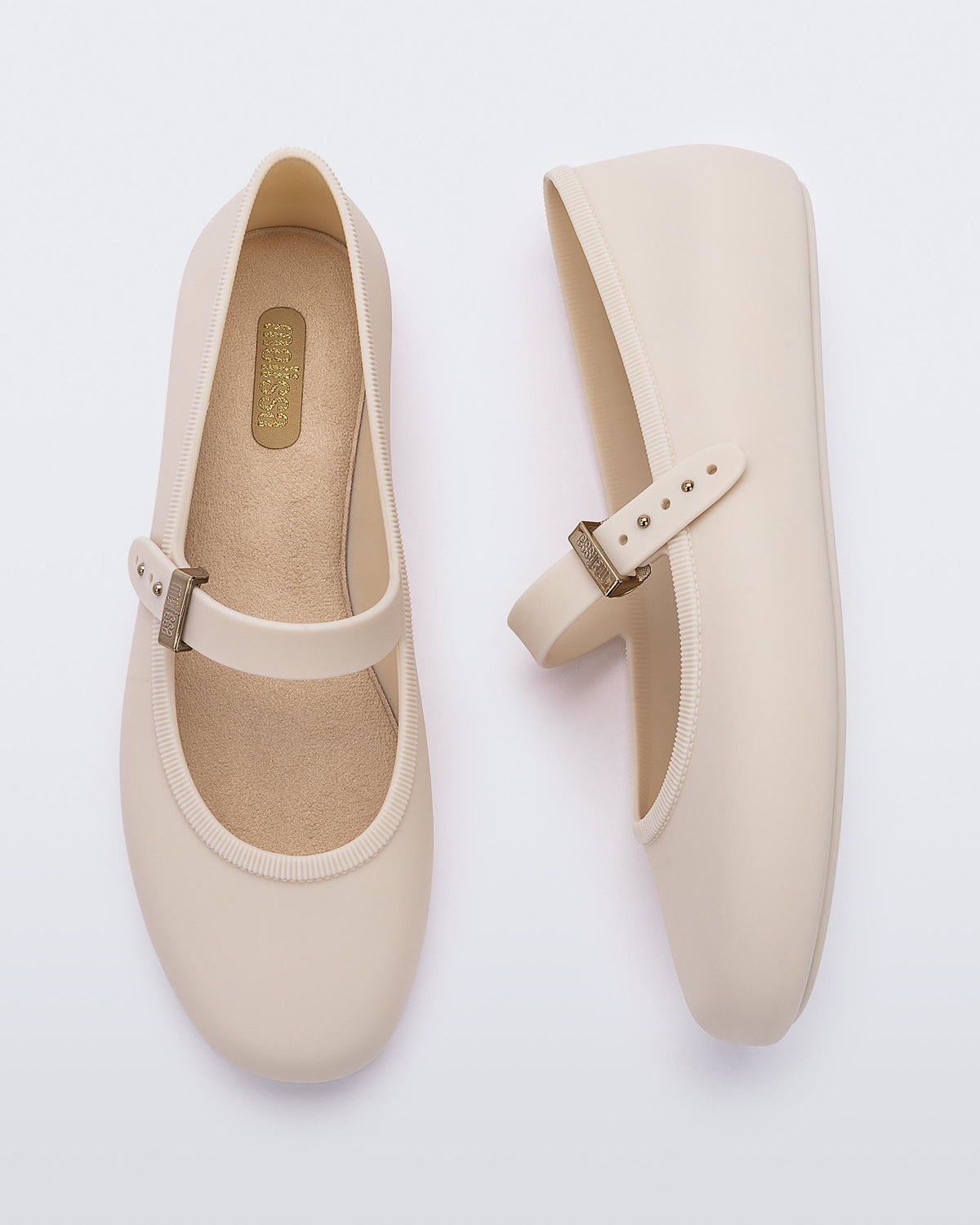 Top and side view of a pair of beige Soft adult flats with strap and gold buckle