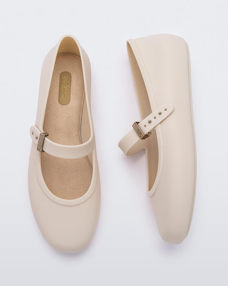 Top and side view of a pair of beige Soft adult flats with strap and gold buckle