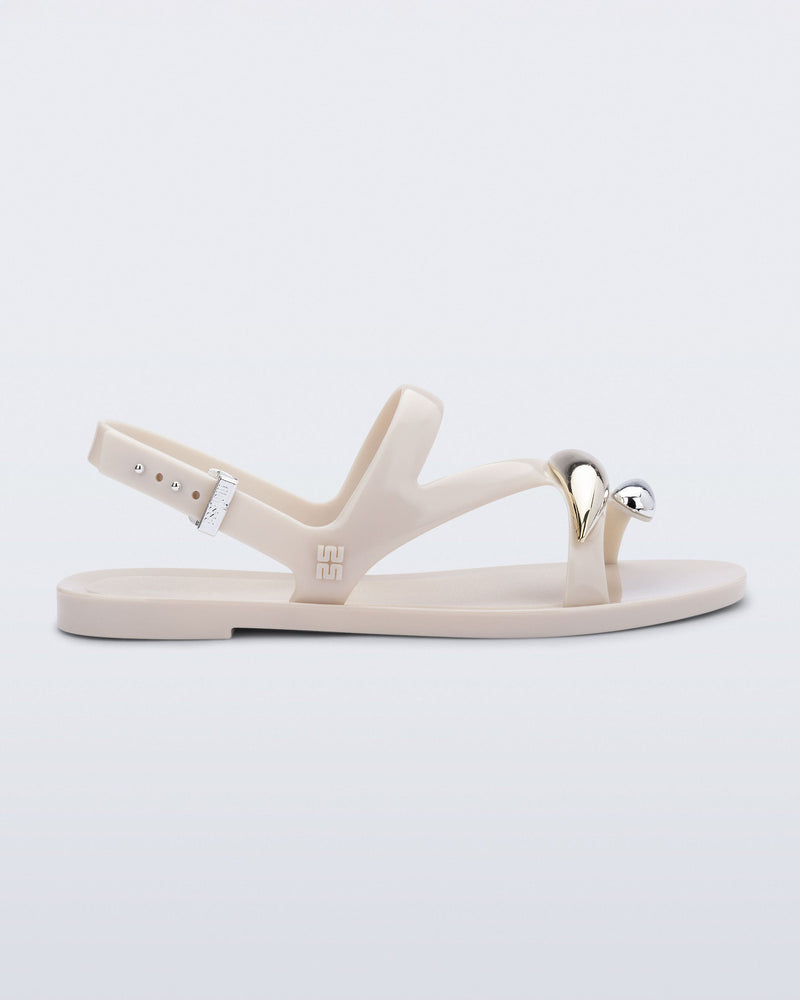 Side view of an beige  Iris sandal with gold upper embellishments