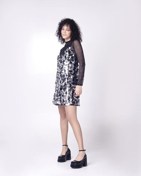 Model in a silver and black cocktail dress wearing a pair of black Melissa Doll Heel platforms with ankle strap.