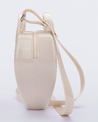 Side view of a beige Heartbeat bag with small handles and longer strap.