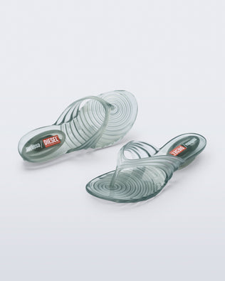 Top and angled view of a pair of transparent green Flip Flop + Diesel sandals
