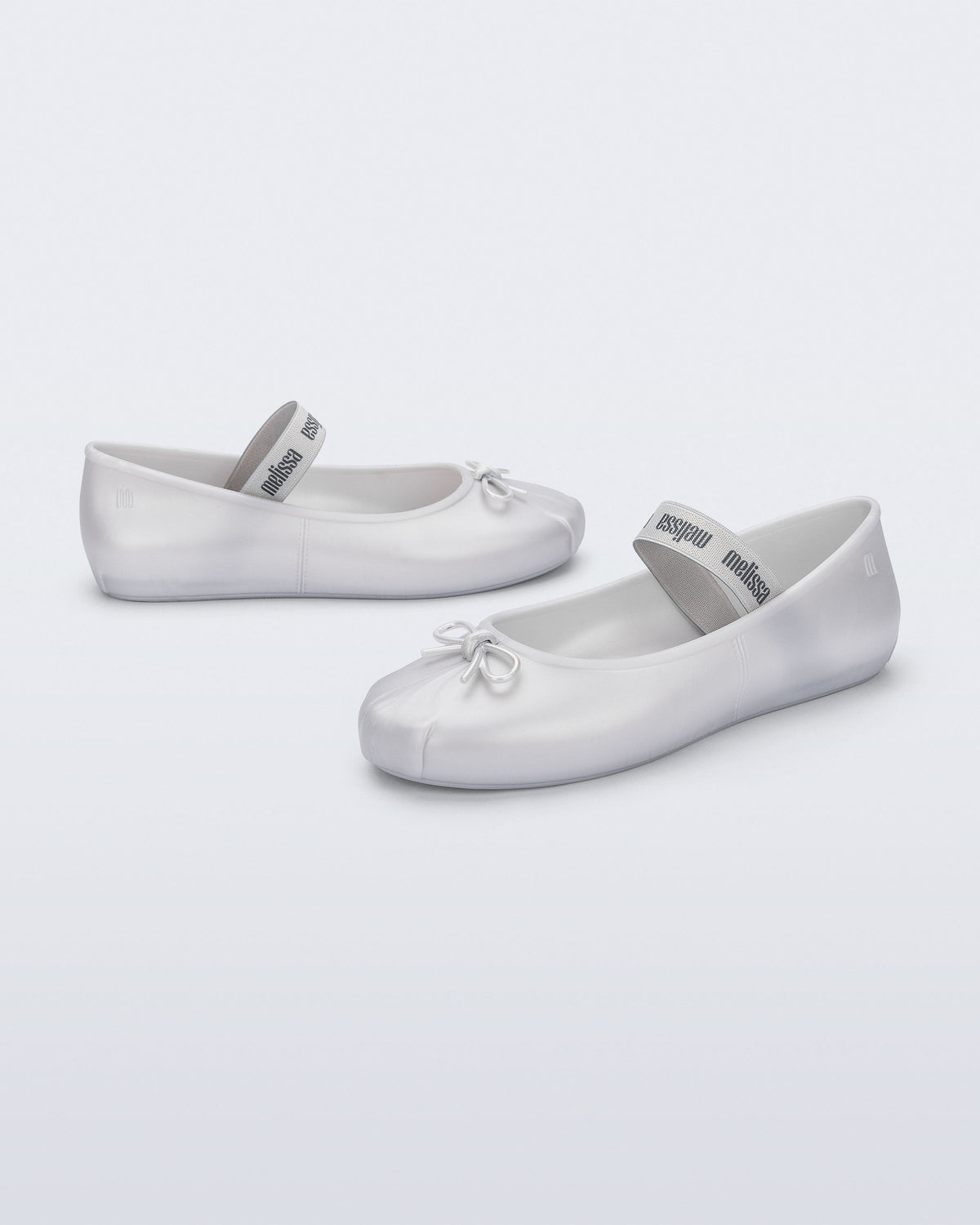 Side and front angled view of a pair of pearly white Sophie flats with top elastic strap and small bow