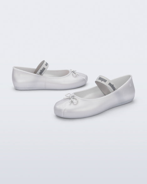 Side and front angled view of a pair of pearly white Sophie flats with top elastic strap and small bow