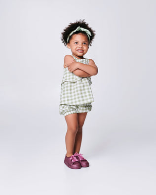 Child model wearing a pair of glitter pink baby Hip M Lover sneakers with laces