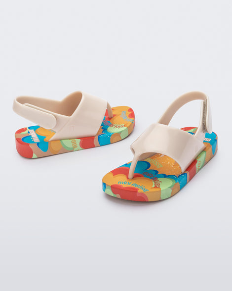 Angled view of a pair of beige Shiny baby sandals with multicolor sole