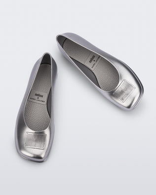 Top and angled view of a pair of metallic silver Ruby + Marc Jacobs flats