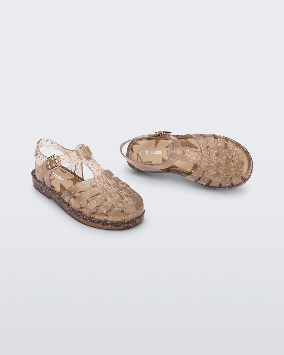 Angled view of a pair of clear beige Possession kids sandals with star glitter
