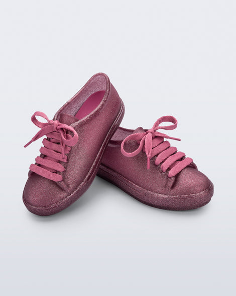 Angled view of a pair of glitter pink kids Hip Sneakers with pink laces