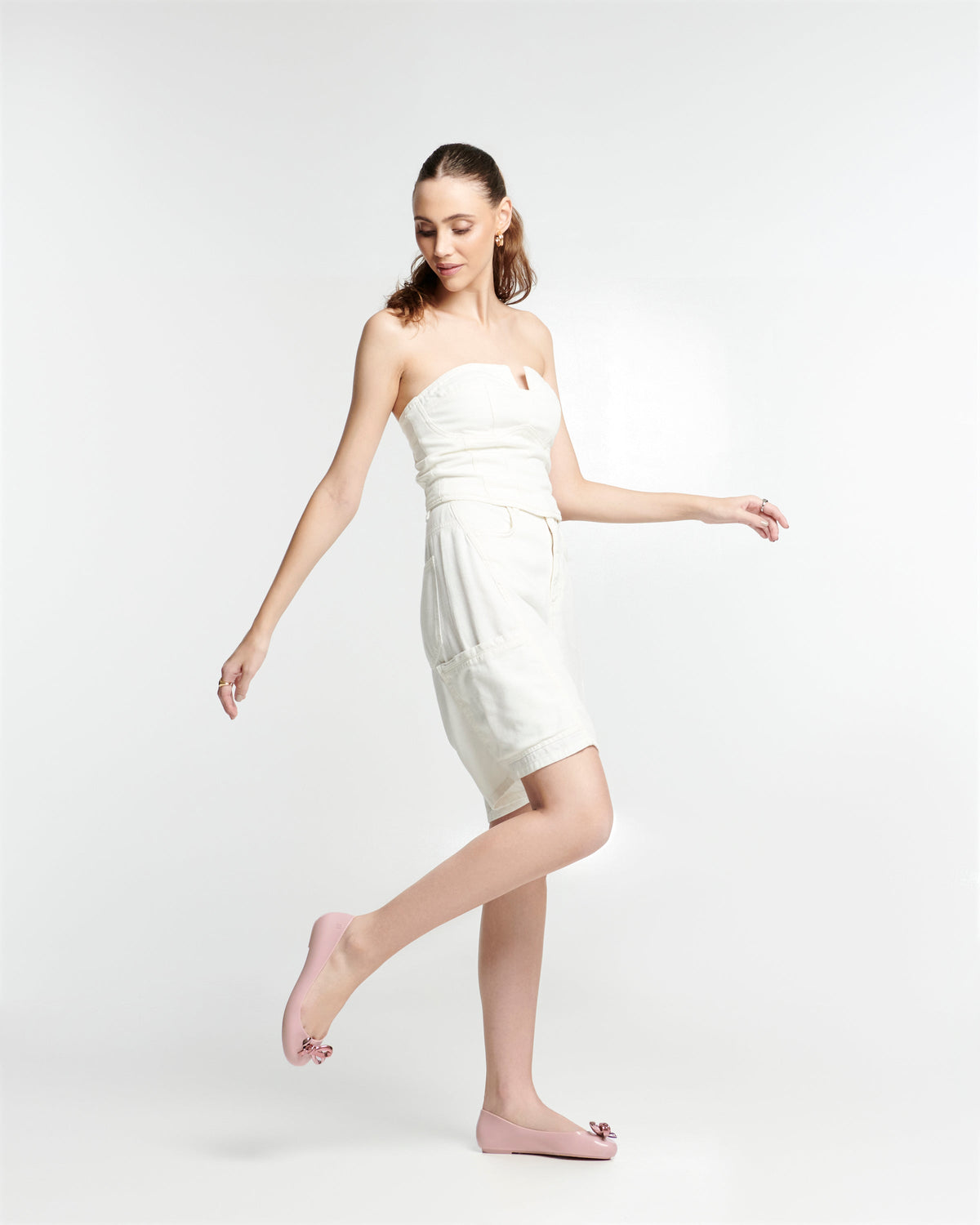 Model in a white dress wearing a pair of pink Sweet Love Glam ballerina flats with pink chrome bow