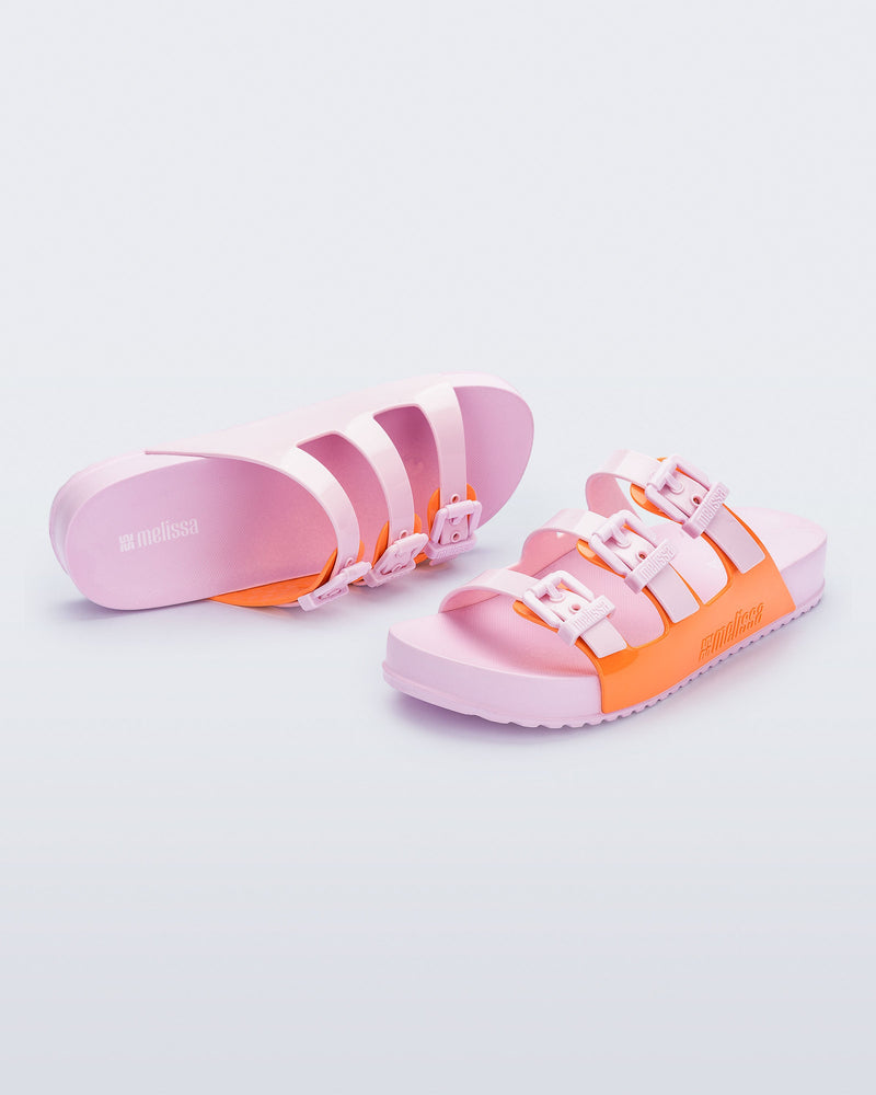 Top and angled view of a pair of pink and orange Cozy Stripes slides