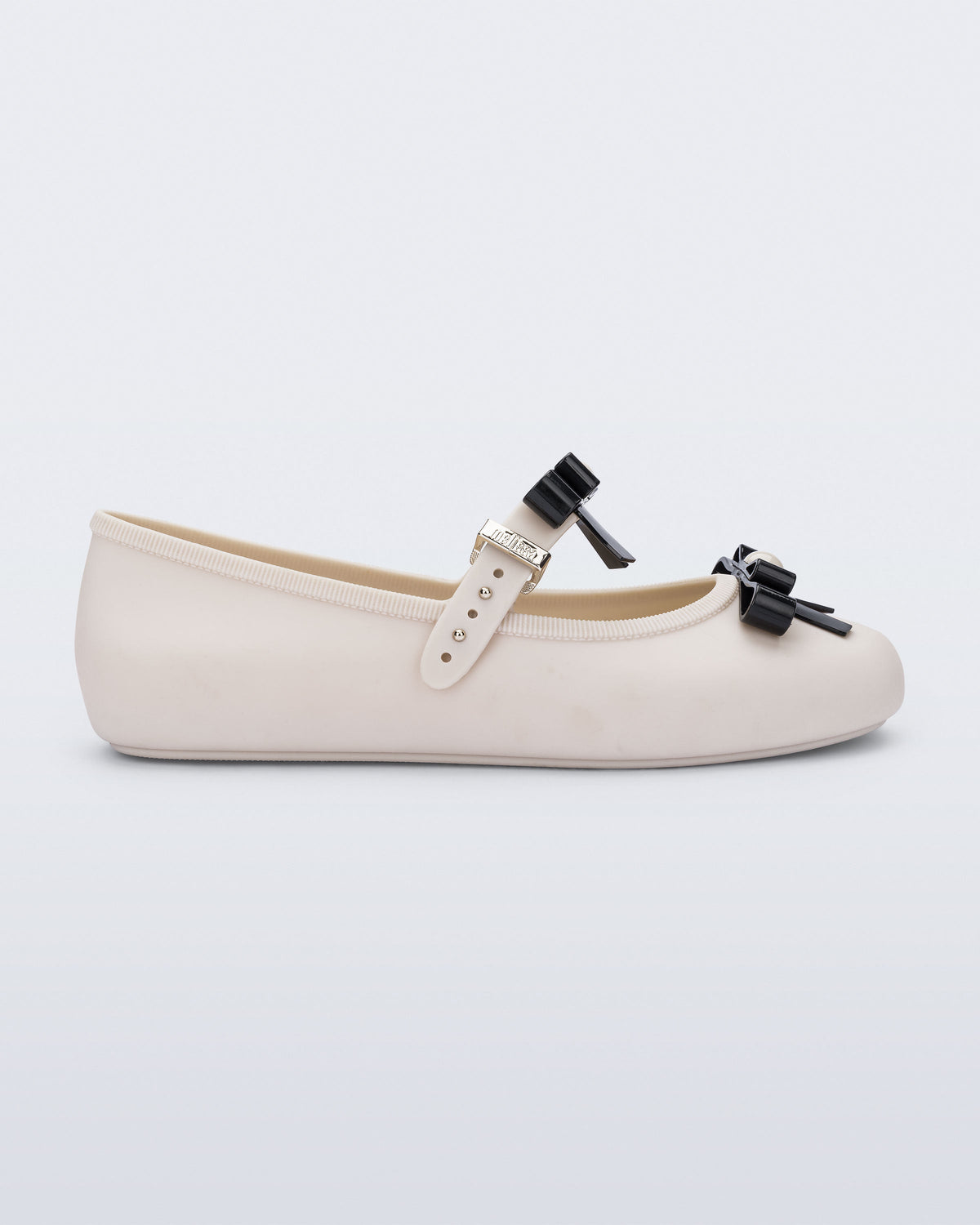 Side view of a beige Soft Ballerina Bow with black bows and a pearl in the center of each bow