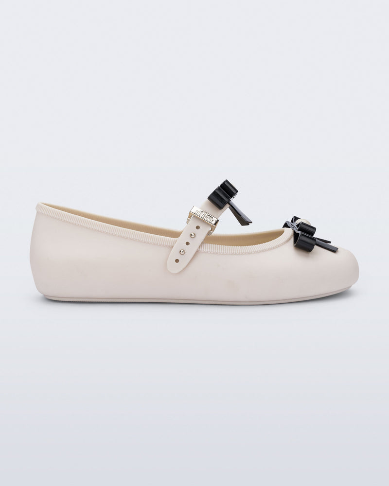 Side view of a beige Soft Ballerina Bow with black bows and a pearl in the center of each bow