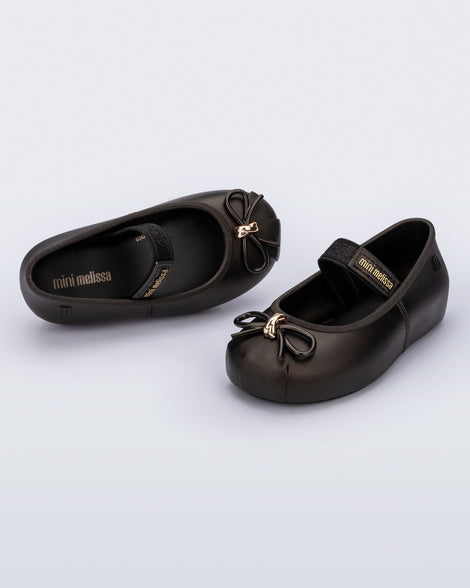 Side and angled view of a pair of metallic black Sophie baby ballerina flats with bow