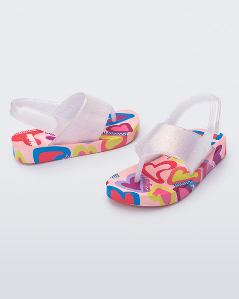 Angled view of a pair of pink glitter Shiny baby sandals with multicolor sole