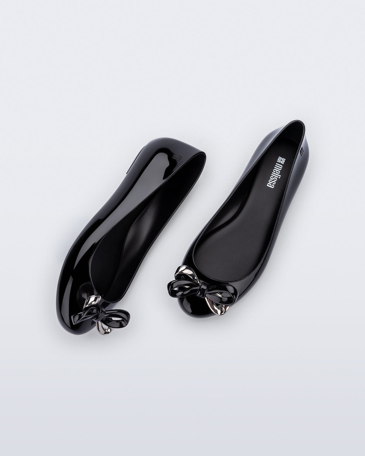 Side and top view of a pair of black Sweet Love Glam ballerina flats with chrome bow