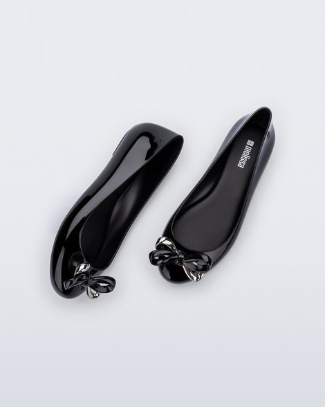 Side and top view of a pair of black Sweet Love Glam ballerina flats with chrome bow
