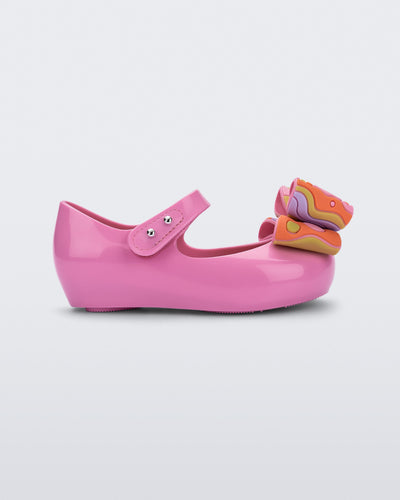 Side view of a pink with multi-color patterned bow Ultragirl Wonderland baby flat