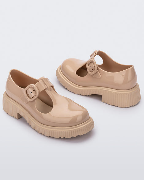Angled side view of a pair of beige Mini Melissa Jackie loafers with two cut outs and a buckle detail strap.