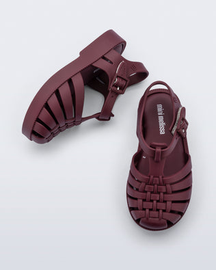 Top and side angled view of a pair of matte burgundy Possession baby fisherman sandals.