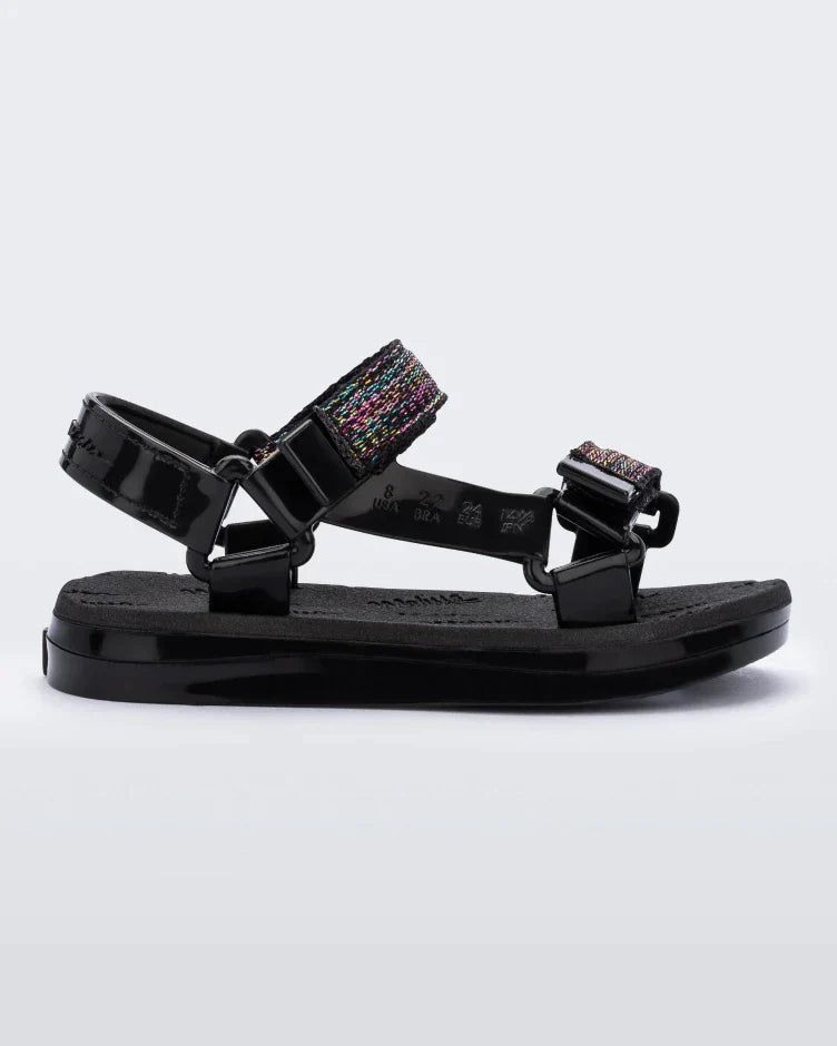 Side view of a black Mini Melissa Papete with glitter and black straps.