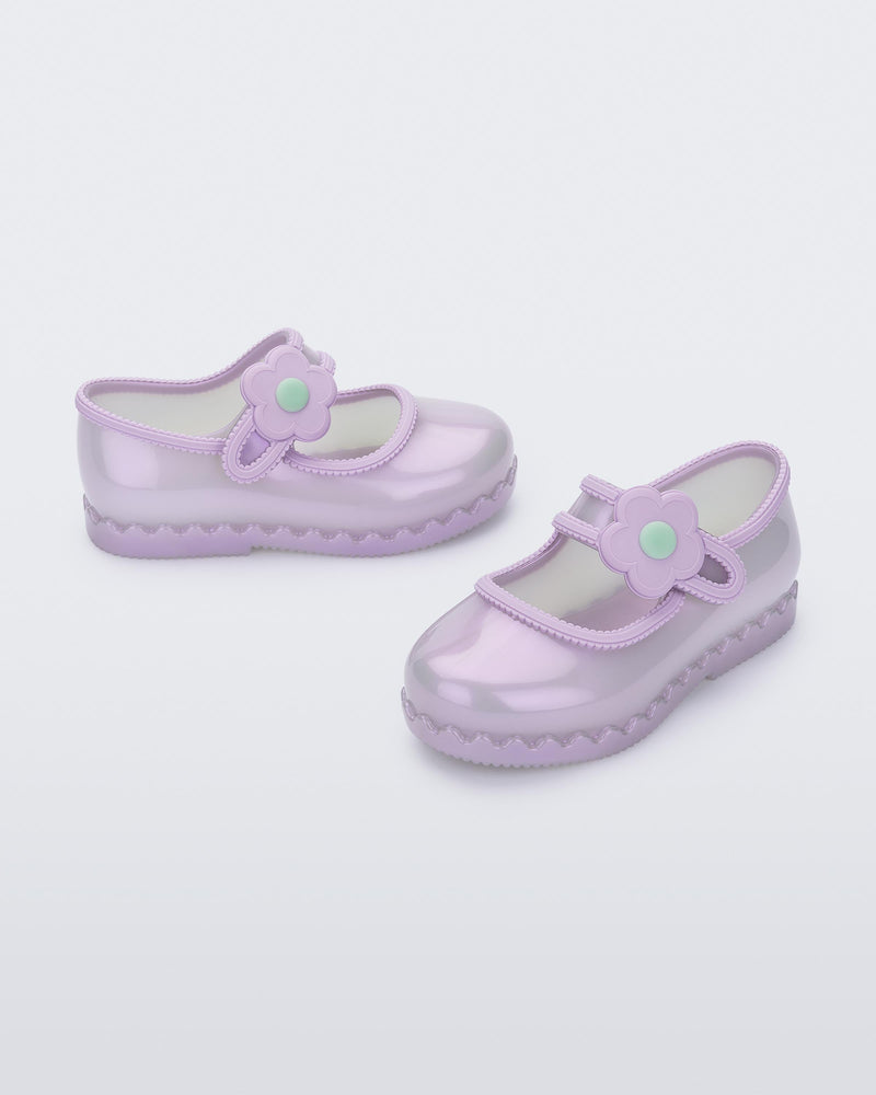 Side and angled view of a pair of pearly lilac Hip Ballerina baby flats with strap with flower