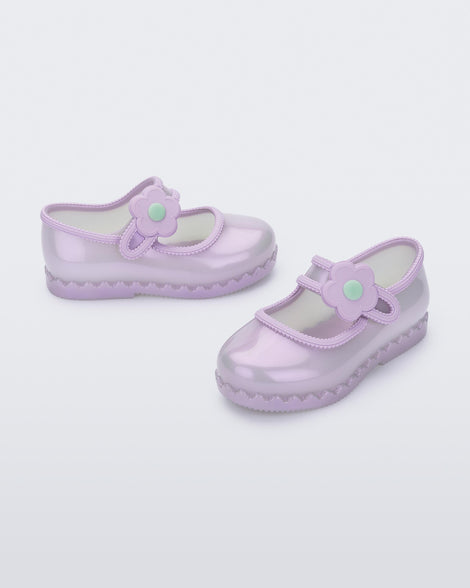 Side and angled view of a pair of pearly lilac Hip Ballerina baby flats with strap with flower