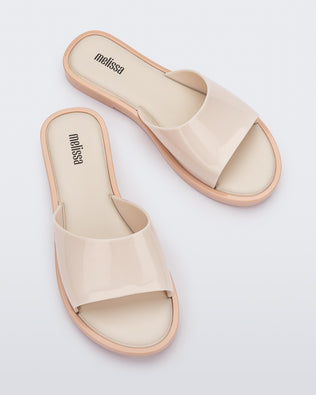 An angled top view of a pair of beige tortoiseshell Melissa Miranda slides