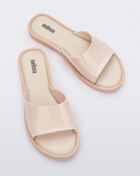 An angled top view of a pair of beige tortoiseshell Melissa Miranda slides
