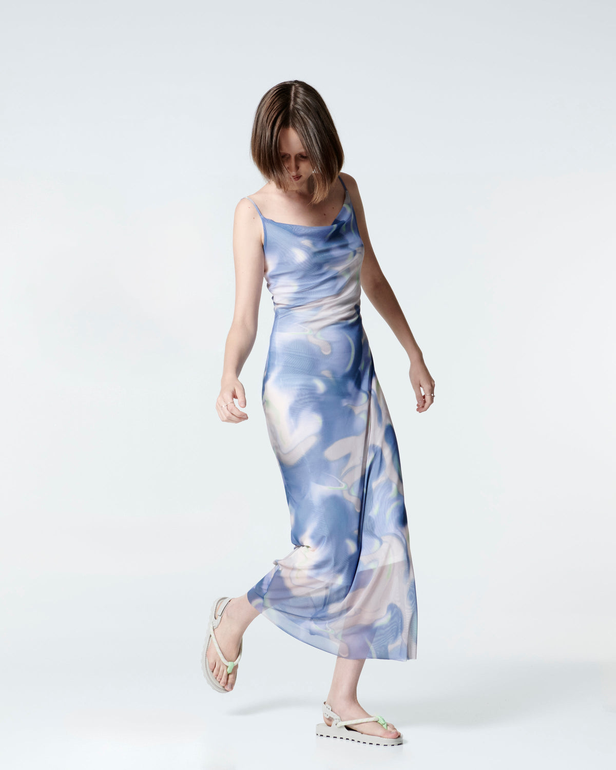 Model in a blue and white dress wearing a pair of beige Bond sandals with textile strap and green toe piece