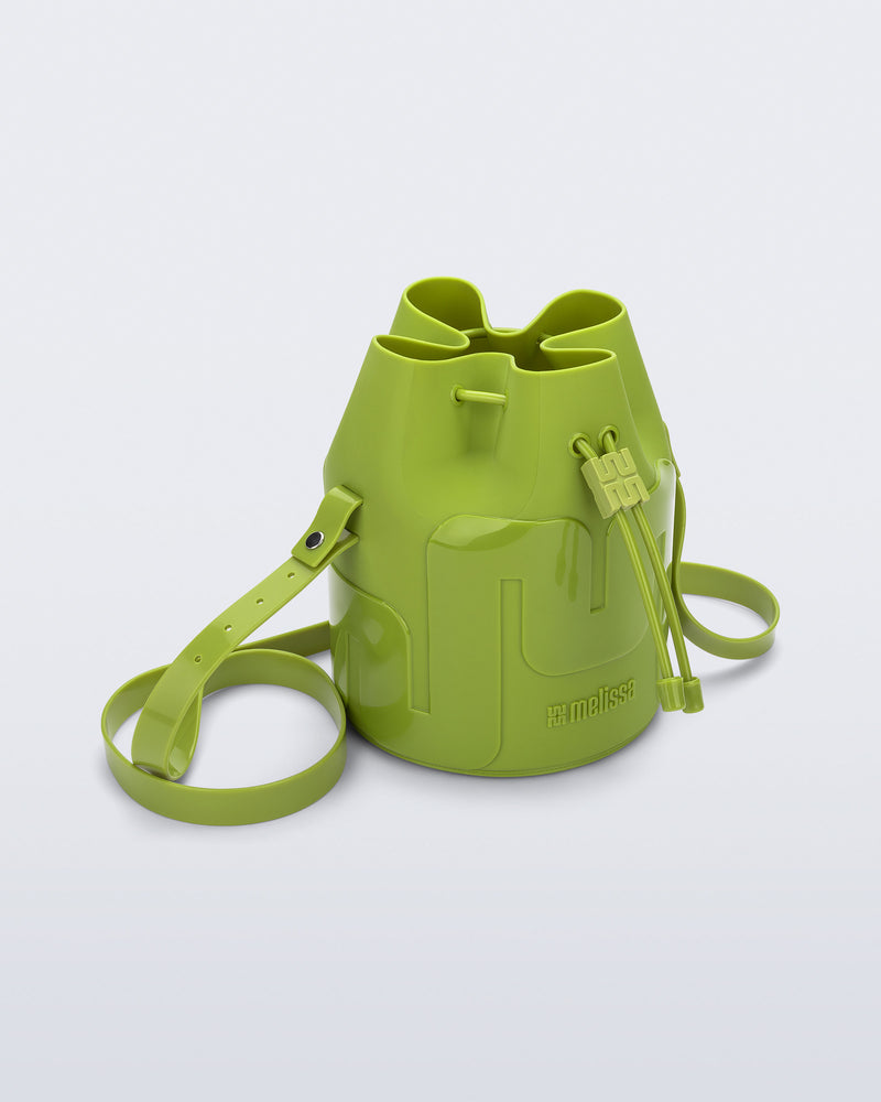 Angled view of a Melissa Station bucket bag in Green. The bag has an adjustable shoulder strap and a drawstring top closure. 