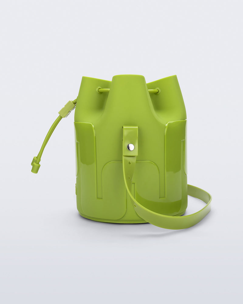 Side view of a Melissa Station bucket bag in Green. The bag has an adjustable shoulder strap and a drawstring top closure. 