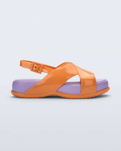 Side view of the Melissa Mare platform sandal. This sandal has two cross straps across the front part of the foot with a thin buckle strap attached. The straps and outsole are orange whiles the platform insole is purple. 