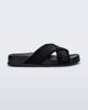 Side view of the Melissa Cozy slide sandals. The slide has two cross straps with Melissa logo embossed onto the straps. The color of the shoe is black. 