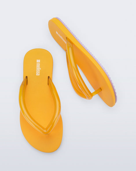 Top and side view a pair of orange Flip Flop Airflow sandal with a clear orange strap and lilac bottom