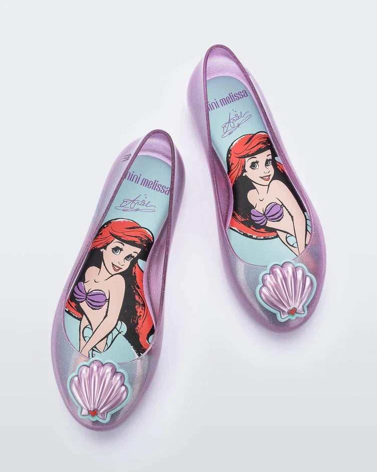 Top view of a pair of purple Mini Melissa Sweet Love Princess flats, with a purple base, Ariel in script on the side, a sea shell detail on the toe, and a drawing of Ariel of The Little Mermaid on the sole.
