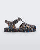 Side view of a Mini Melissa Possession fisherman sandal in black with all over Disney character print. There is a buckle closure on the side of the ankle strap. 