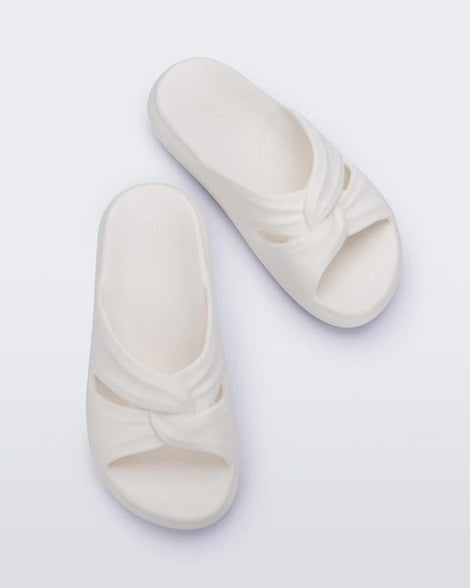 Top view of a pair of white Melissa Free Slides with a twist front detail.