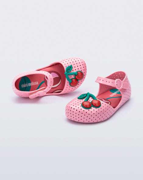 Angled and top view of a pair of pink Pop baby flats with two red cherries
