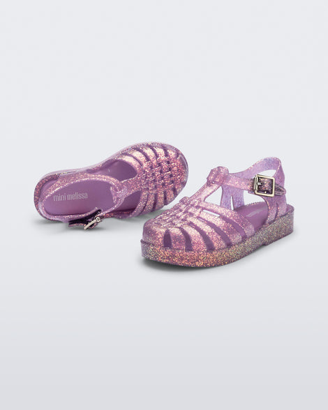 Top and angled view of a pair of glitter lilac baby Possession sandals