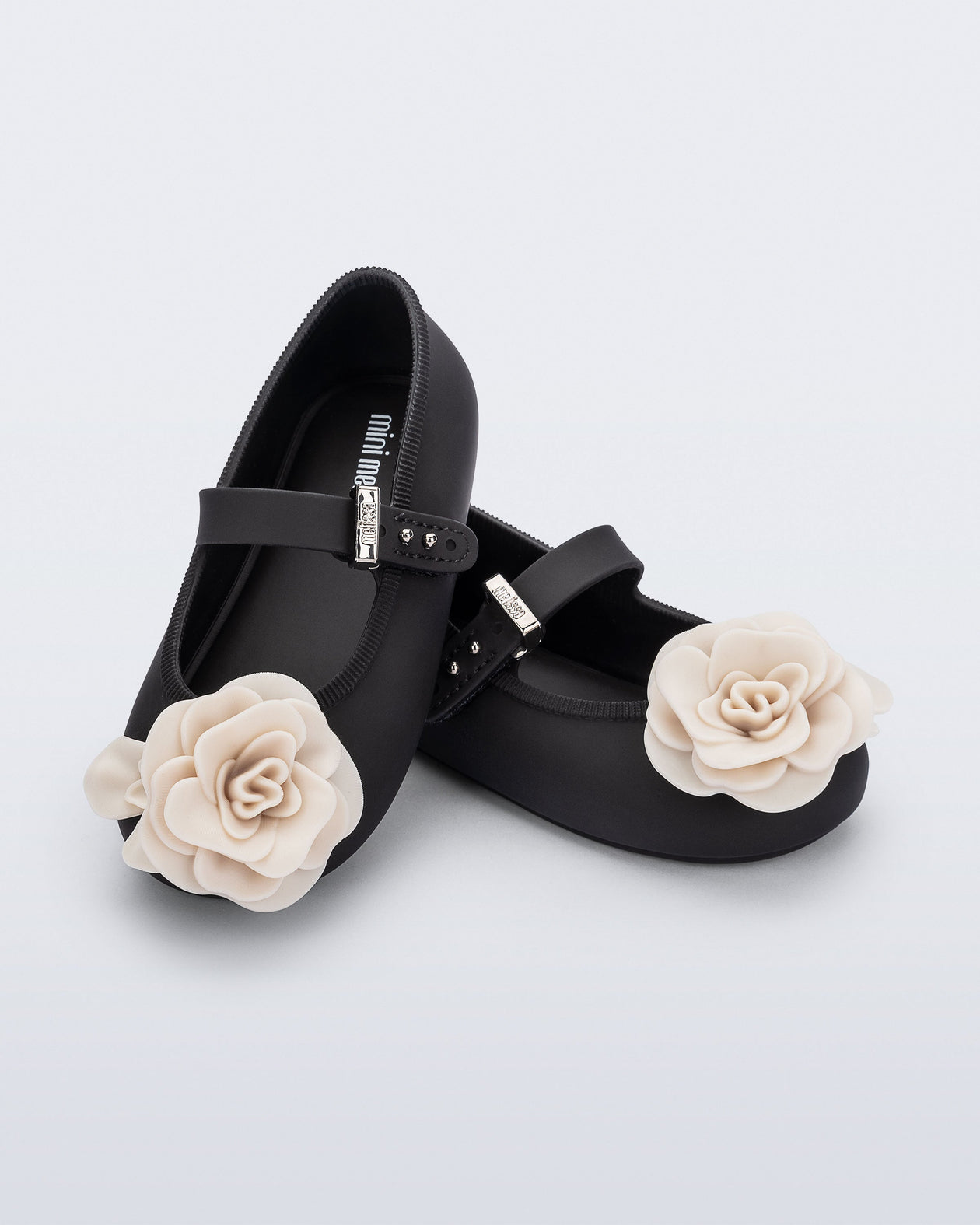 Angled view of a pair of black Soft Ballerina baby flats with beige flowers