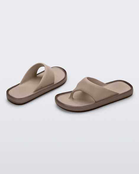 Angled view of a pair of beige Float flip flops