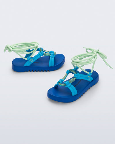 Side and angled view of a pair of blue sole, blue upper, and green ankle strap Kirk + Alexandre Pavao sandals