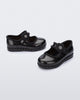 Side and angled view of a pair of black Hip Ballerina baby flats with strap with flower