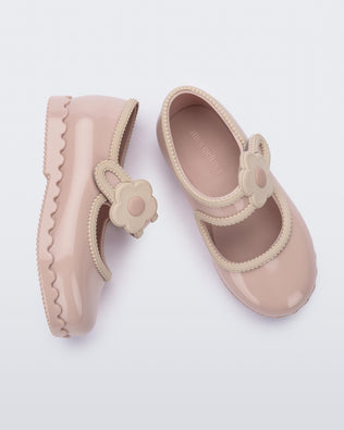 Side and top view of a pair of beige Hip Ballerina baby flats with strap with flower