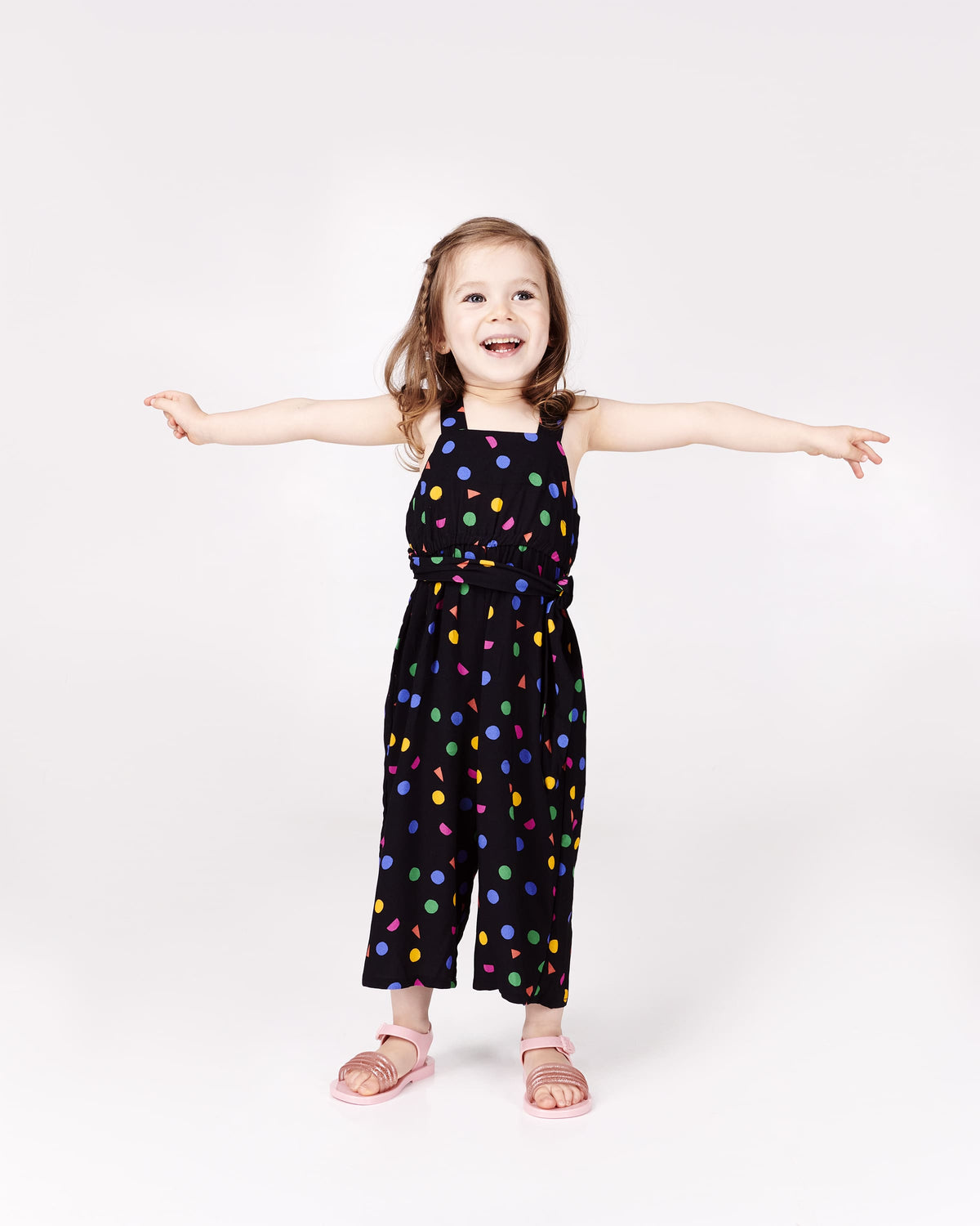 Toddler model in black patterned outfit wearing a pair of pink Mar Wave baby sandals.