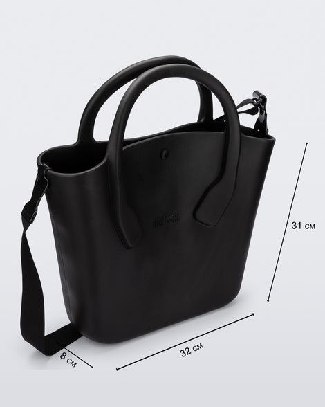 Angled view of a black Free Big Bag with handles and a strap and dimensions 32 cm length, 8 cm width, 31 cm height