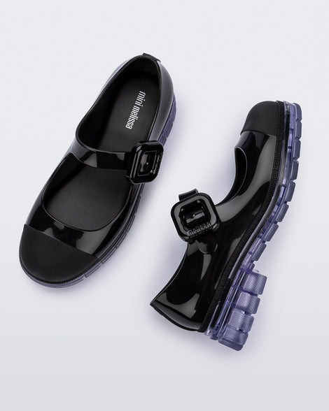 Top and side  view of a pair of black with clear sole June kids mary janes with matte toe cap