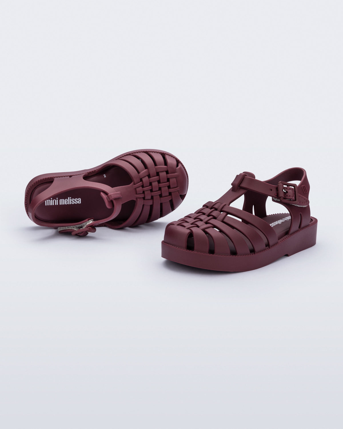 Top and side angled view of a pair of matte burgundy Possession baby fisherman sandals.