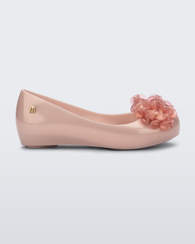 Side view of a pearly pink Ultragirl Springtime kids flat with two clear pink flowers and peep toe.